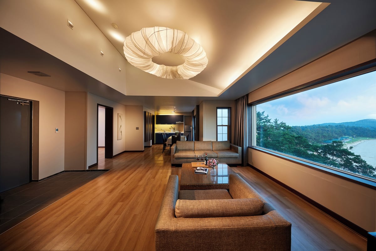 A spacious living area with a large window, a modern ceiling light, and a view of the outdoors.