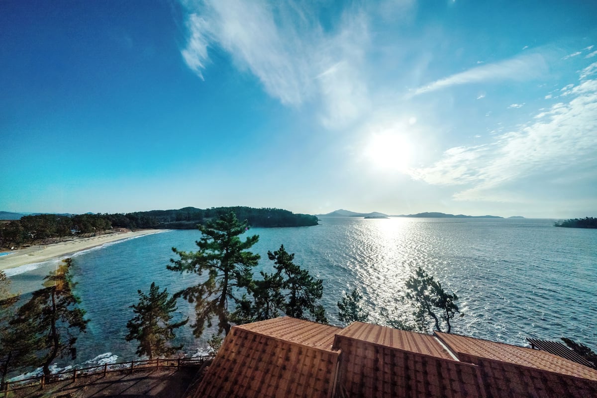 A coastal view with a beach, a large body of water, and distant islands.