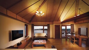 Una habitación amplia con techo de madera, un televisor de pantalla plana, un sofá, una mesa de comedor y vistas al exterior.