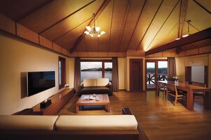 Una habitación amplia con techo de madera, un televisor de pantalla plana, un sofá, una mesa de comedor y vistas al exterior.