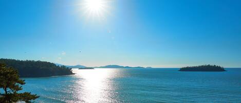 Una playa con agua cristalina, cielo soleado y islas a lo lejos.