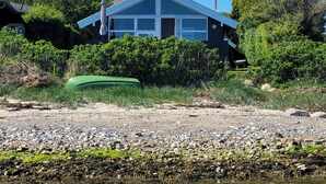 Una casa con techo a dos aguas, ventanas amplias y una bandera.
