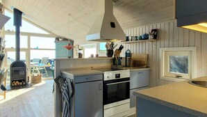 Una cocina con estufa de leña, un lavamanos y una ventana.
