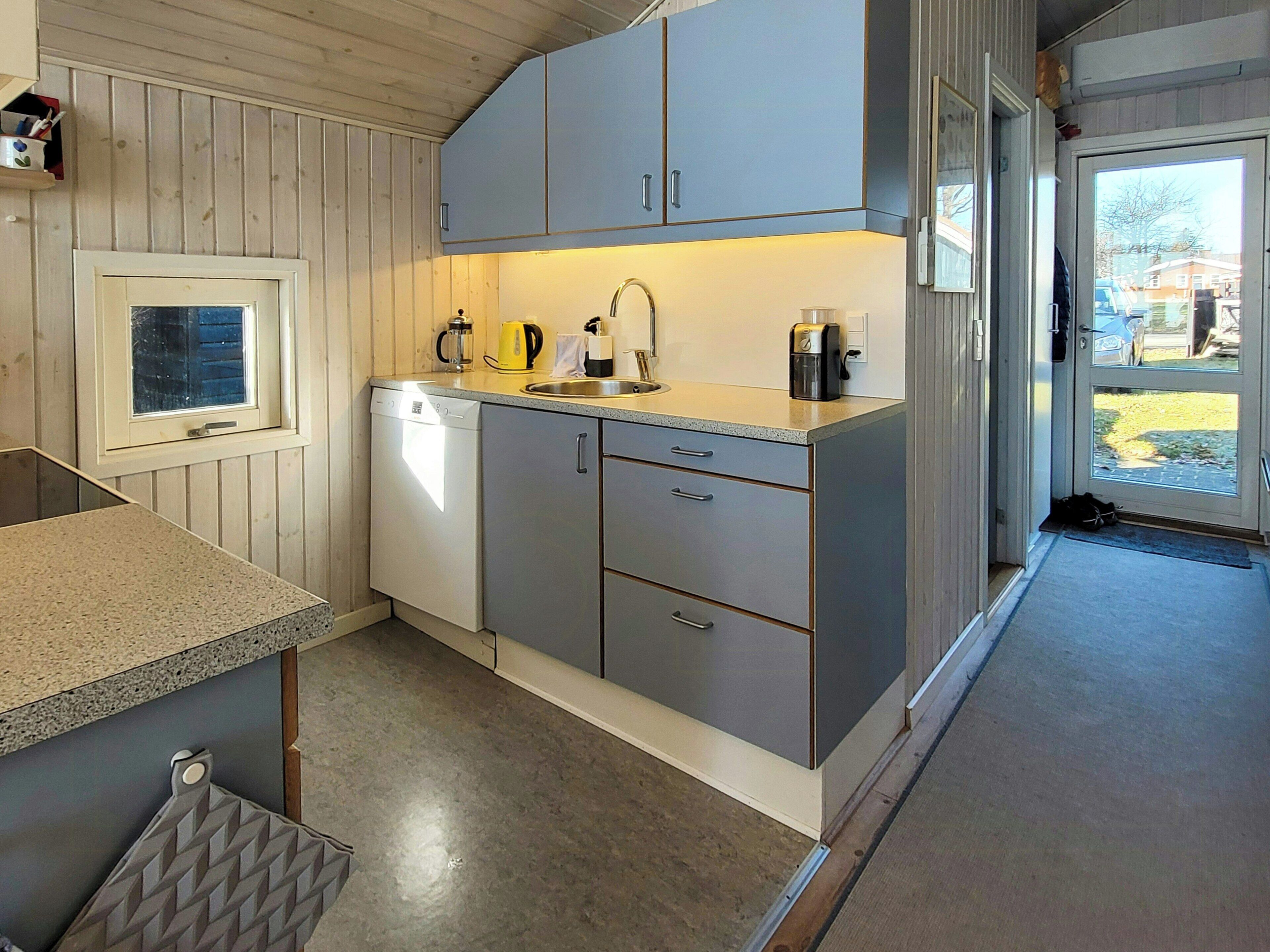 A compact kitchen with a dishwasher, a sink, and a coffee maker.