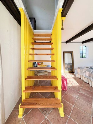 A staircase with wooden steps and yellow railings leading to a bedroom with a bed and a window. - Rural guest house between Simrishamn and Skillinge (Simrishamn)