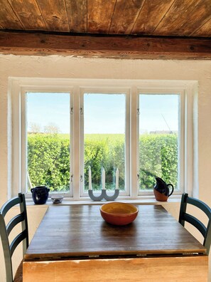A dining table with chairs, a candle holder, and a pitcher on a windowsill. - Rural guest house between Simrishamn and Skillinge (Simrishamn)