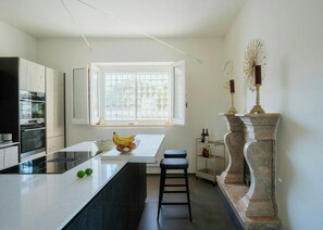 A modern kitchen with a large island, built-in oven, and a window with a view. - Contemporary villa among ancient olives in Puglia (Ostuni)