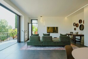 A modern living room with a sofa, a dining table, and a large window. - Contemporary villa among ancient olives in Puglia (Ostuni)