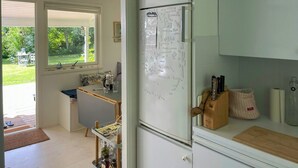 A kitchen with a refrigerator, a window, a dining table, and a view of the outdoors.