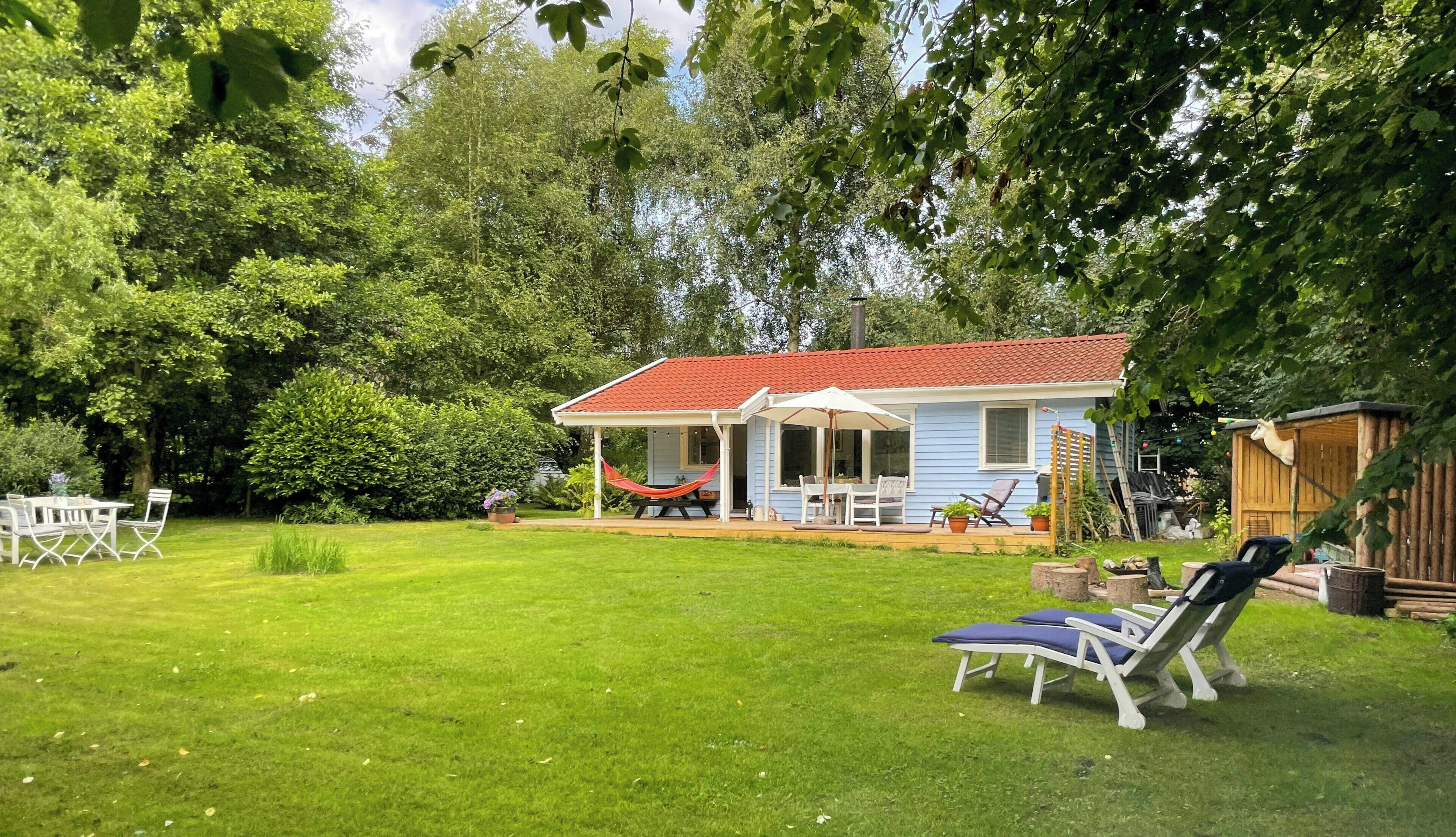 A house with a red roof, a covered patio, and a lawn.