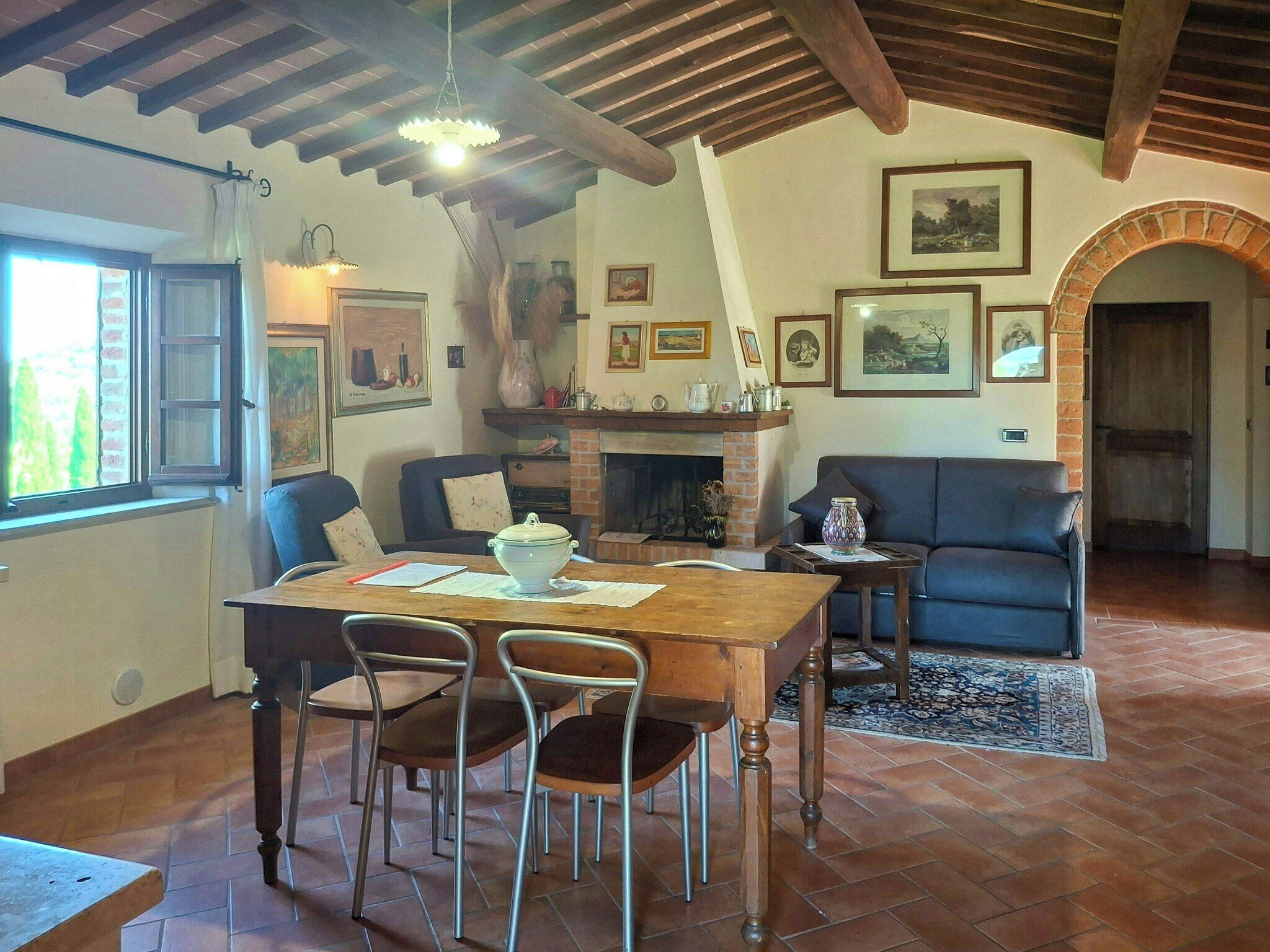 A dining area with a wooden table, chairs, a fireplace, and a sofa.