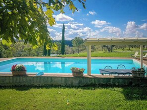 Ein Swimmingpool mit Pergola, Gartenmöbeln und Blumentöpfen.