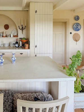 A kitchen with a central island, white cabinetry, and a dining area with a chair. - Charming farmhouse with open spaces near Österlen (Löderup)