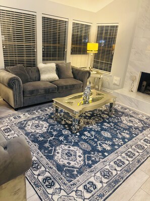 Ein Wohnzimmer mit einer Couch, einem Couchtisch, einem gemusterten Teppich und einem Kamin.