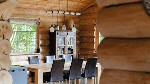 Un interior de madera con una mesa de comedor, sillas y lámparas colgantes.