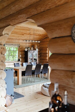 A wooden interior with a dining table, chairs, and hanging light fixtures. - Modern log cabin by Dalby Huse beach (Dalby Huse)