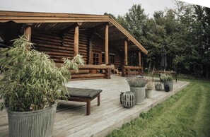 A log cabin with a wooden deck, outdoor seating, and potted plants. - Modern log cabin by Dalby Huse beach (Dalby Huse)