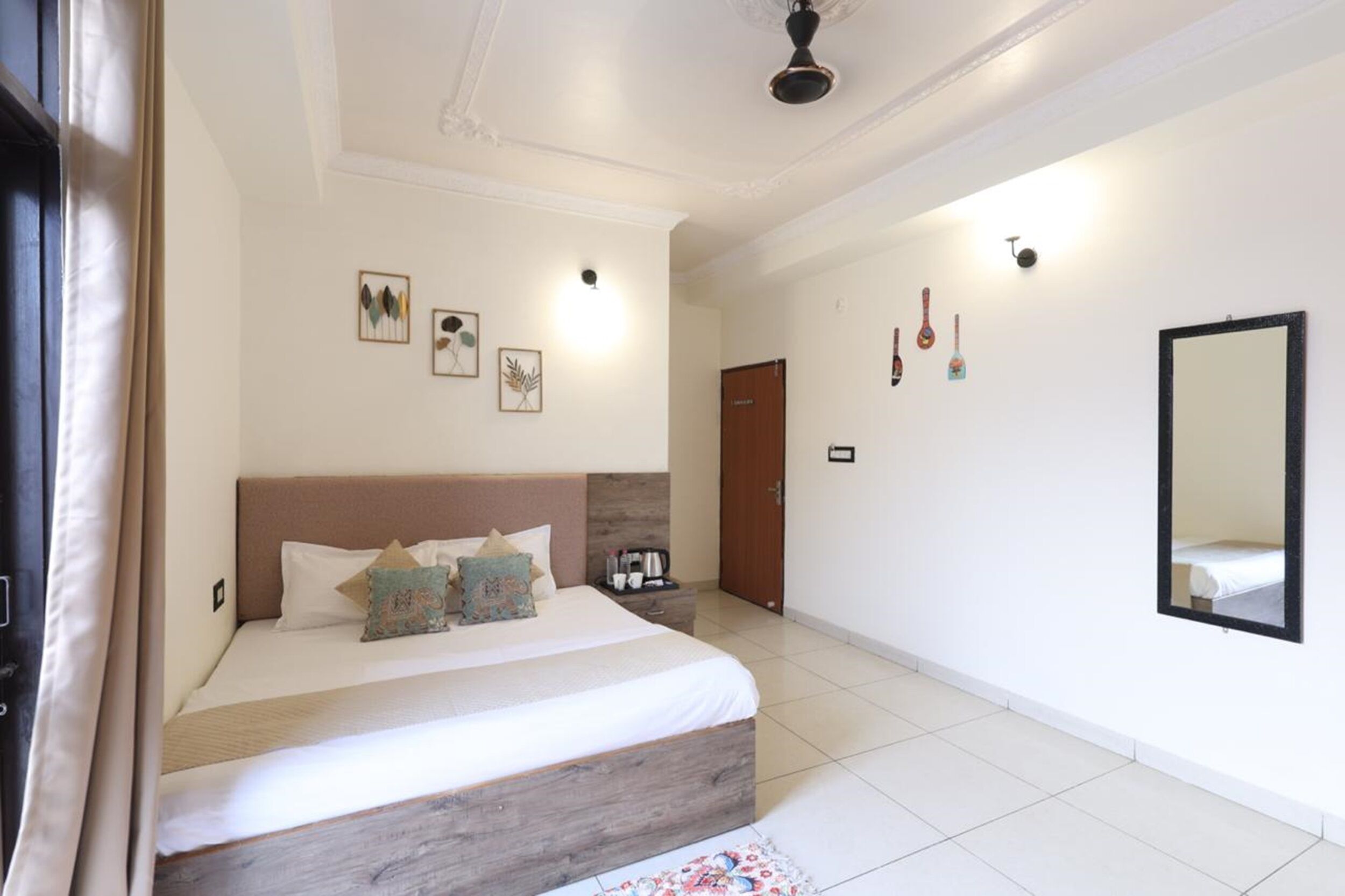 A bedroom with a bed, a nightstand, a mirror, and wall-mounted decorations.