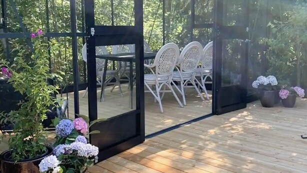 Un patio couvert avec une table et des chaises, entouré de plantes en pot et d’une terrasse en bois.
