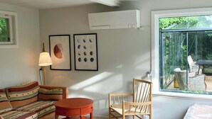 Une pièce comprenant un canapé, une table ronde, une chaise, une lampe et une fenêtre donnant sur un paysage verdoyant.