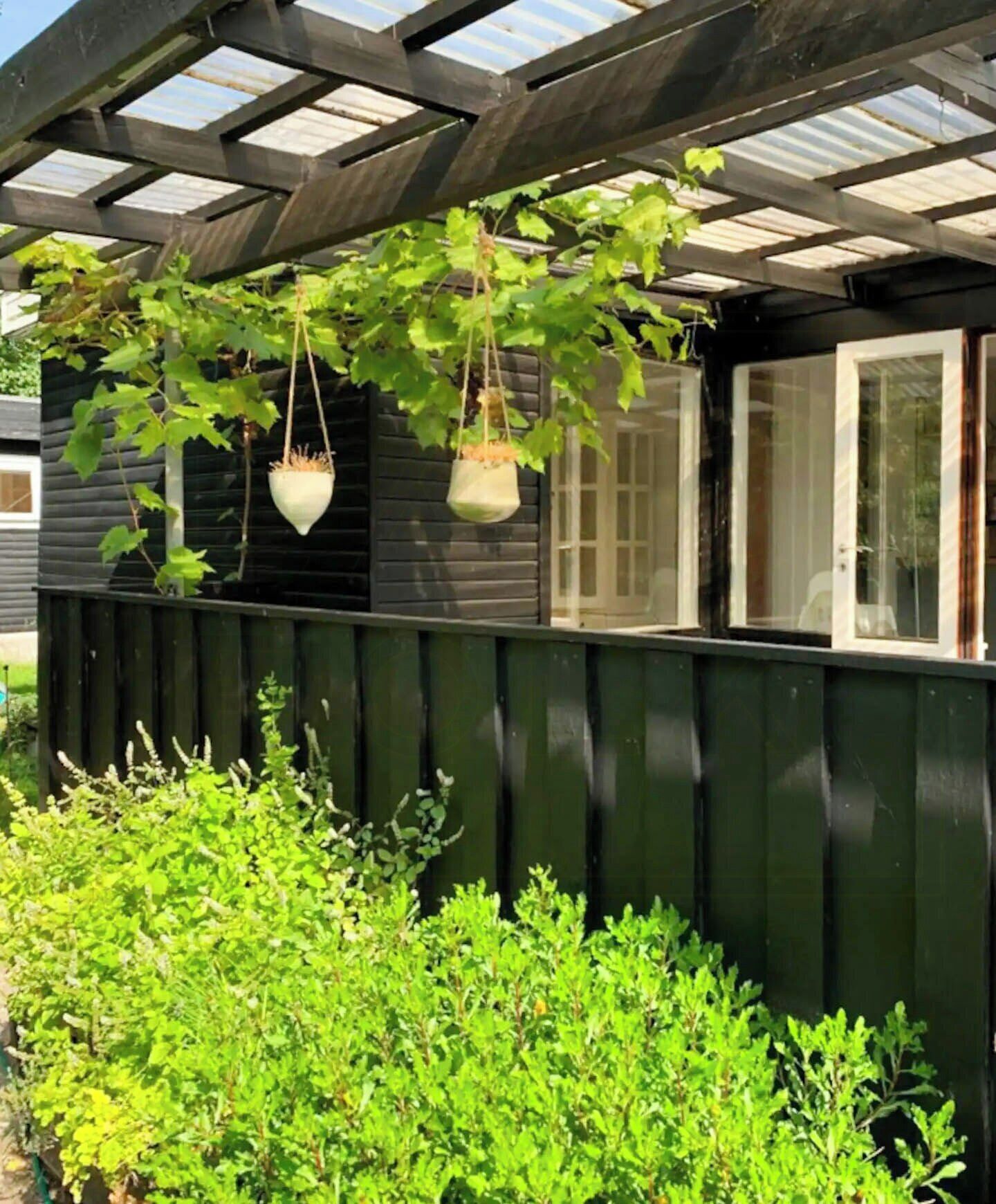 Une structure en bois dotée d’une fenêtre et de jardinières suspendues.