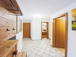 Ein Flur mit einem Holzkabinett, einer Tür und einem Fliesenboden.