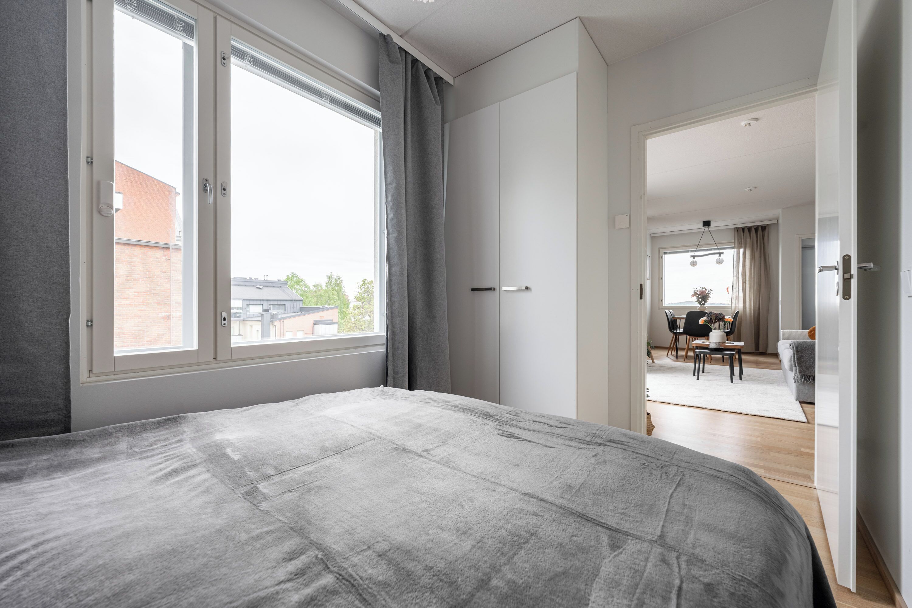 Quarto com cama grande, guarda-roupa e vista pela janela.
