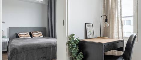 Un dormitorio con cama, mesita de noche, lámpara y vistas al exterior.