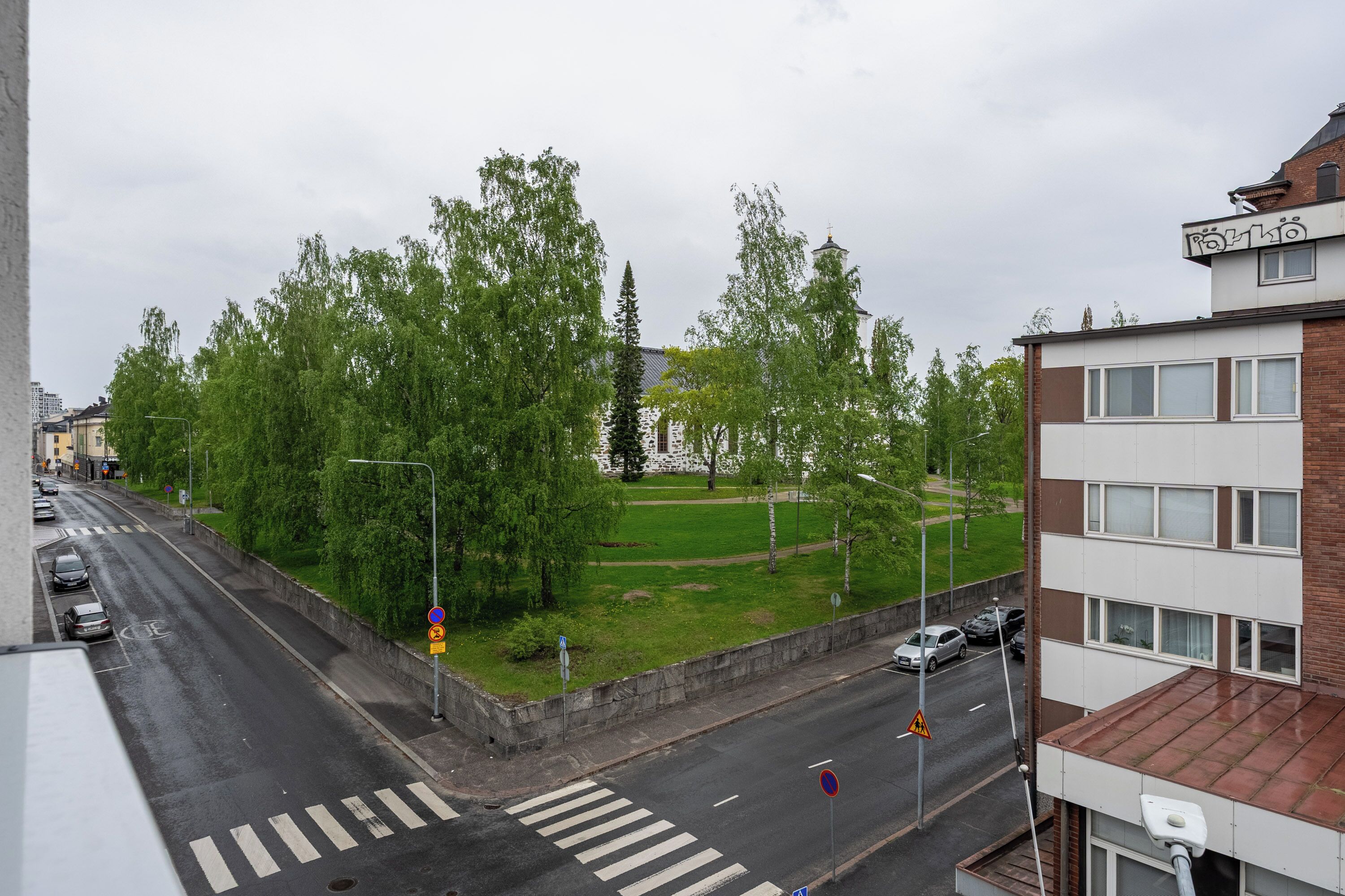 A street view with a pedestrian crossing, cars, and buildings.