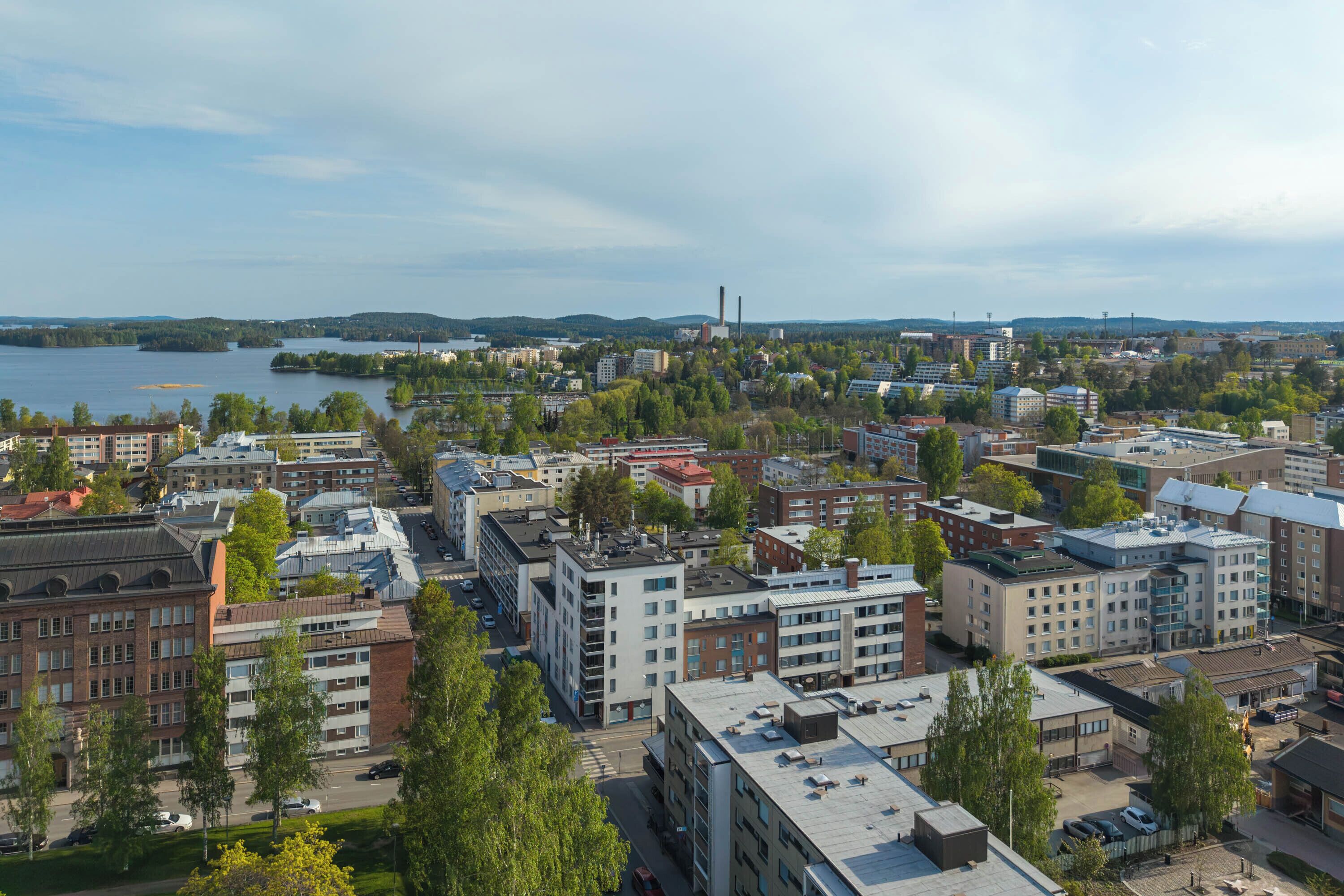 Une vue urbaine avec des bâtiments, une rivière et une cheminée d’usine au loin.