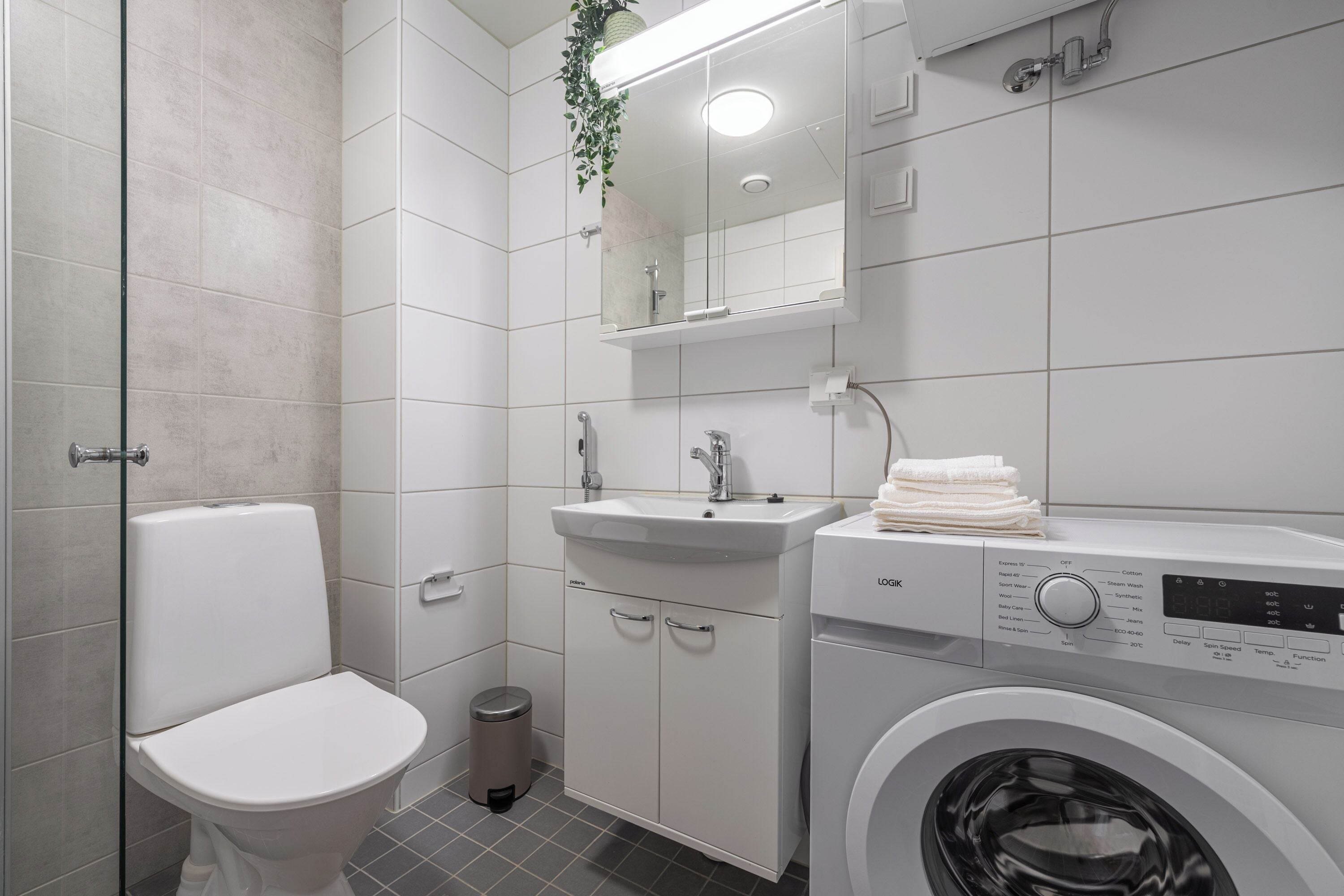 Et moderne badeværelse med toilet, håndvask og vaskemaskine.