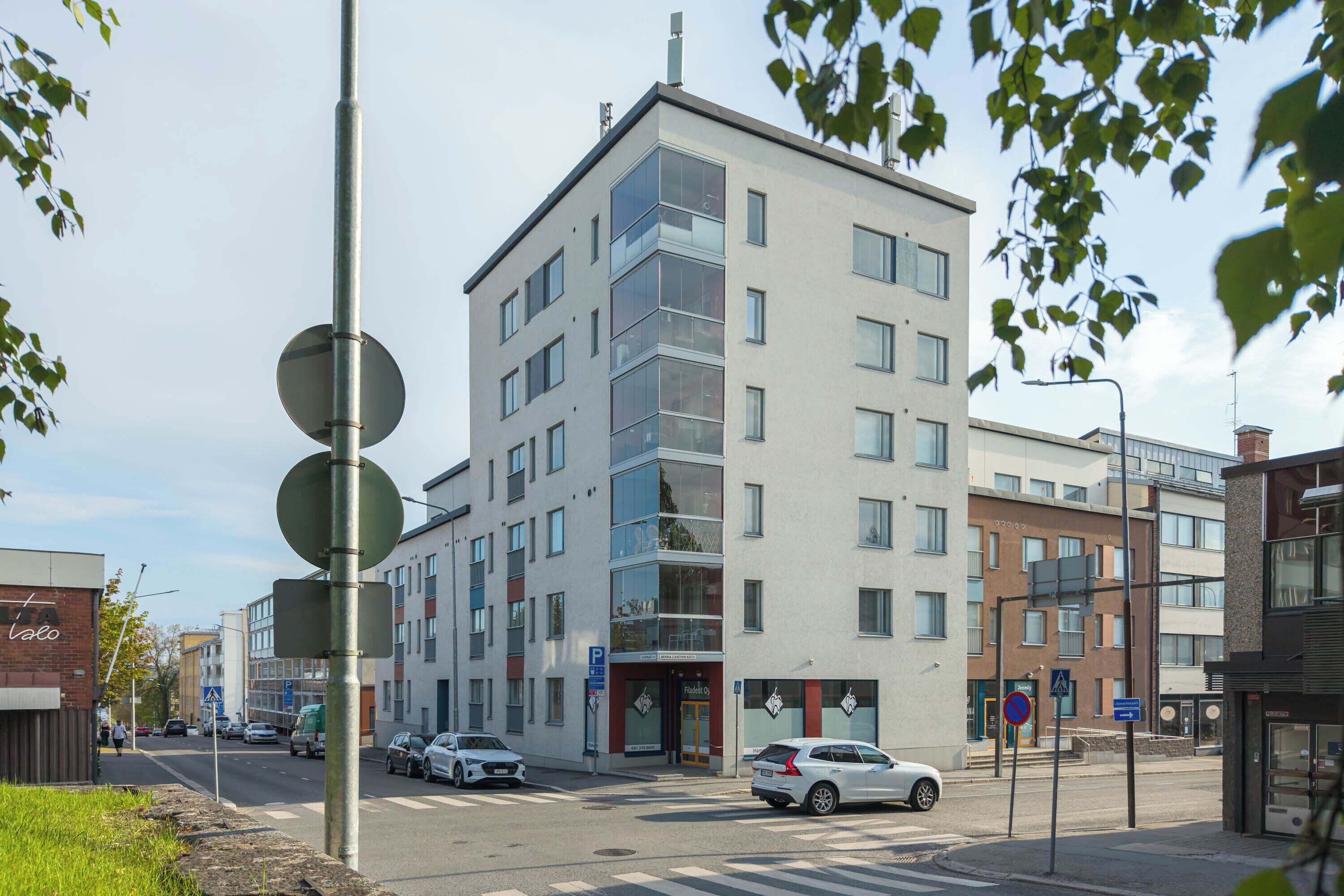 A multi-story building with a modern design, featuring a mix of glass and concrete facades, and a visible entrance with a door and signage.
