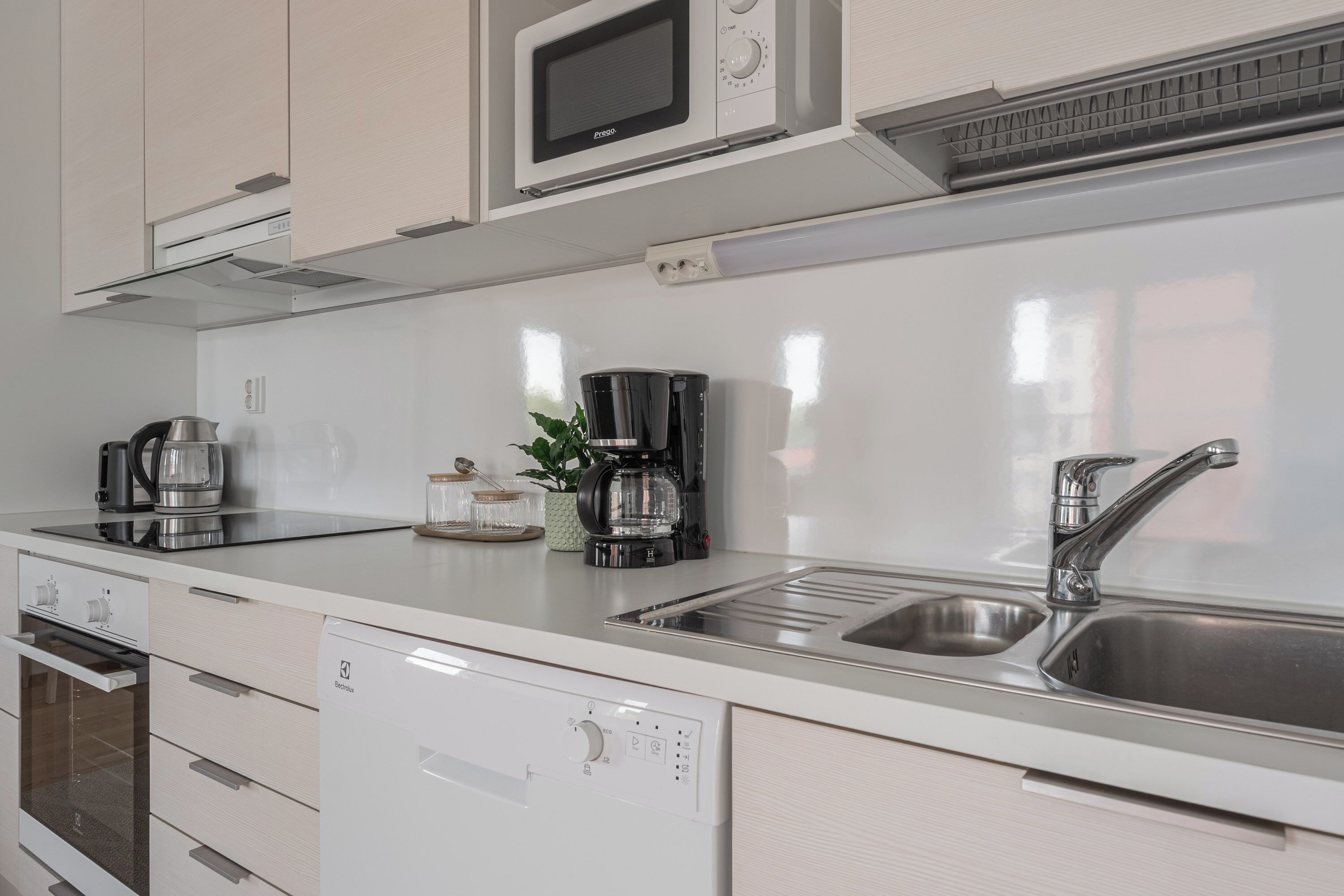 Een moderne keuken met een ingebouwde magnetron, koffiezetapparaat en vaatwasser.