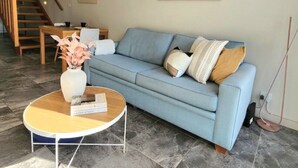 A living room with a sofa, coffee table, and artwork on the wall. - Bright Turner Apartment with Parking and WiFi (Turner)