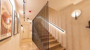 Un escalier moderne avec une rampe en métal, des marches en bois et un luminaire fixé au mur.
