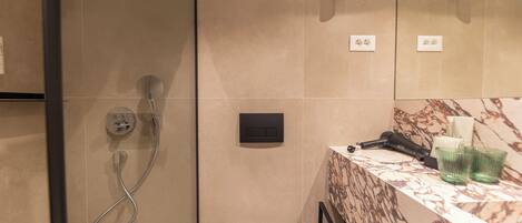 Ett badrum med dusch, toalett, handfat och en bänkskiva i marmor.