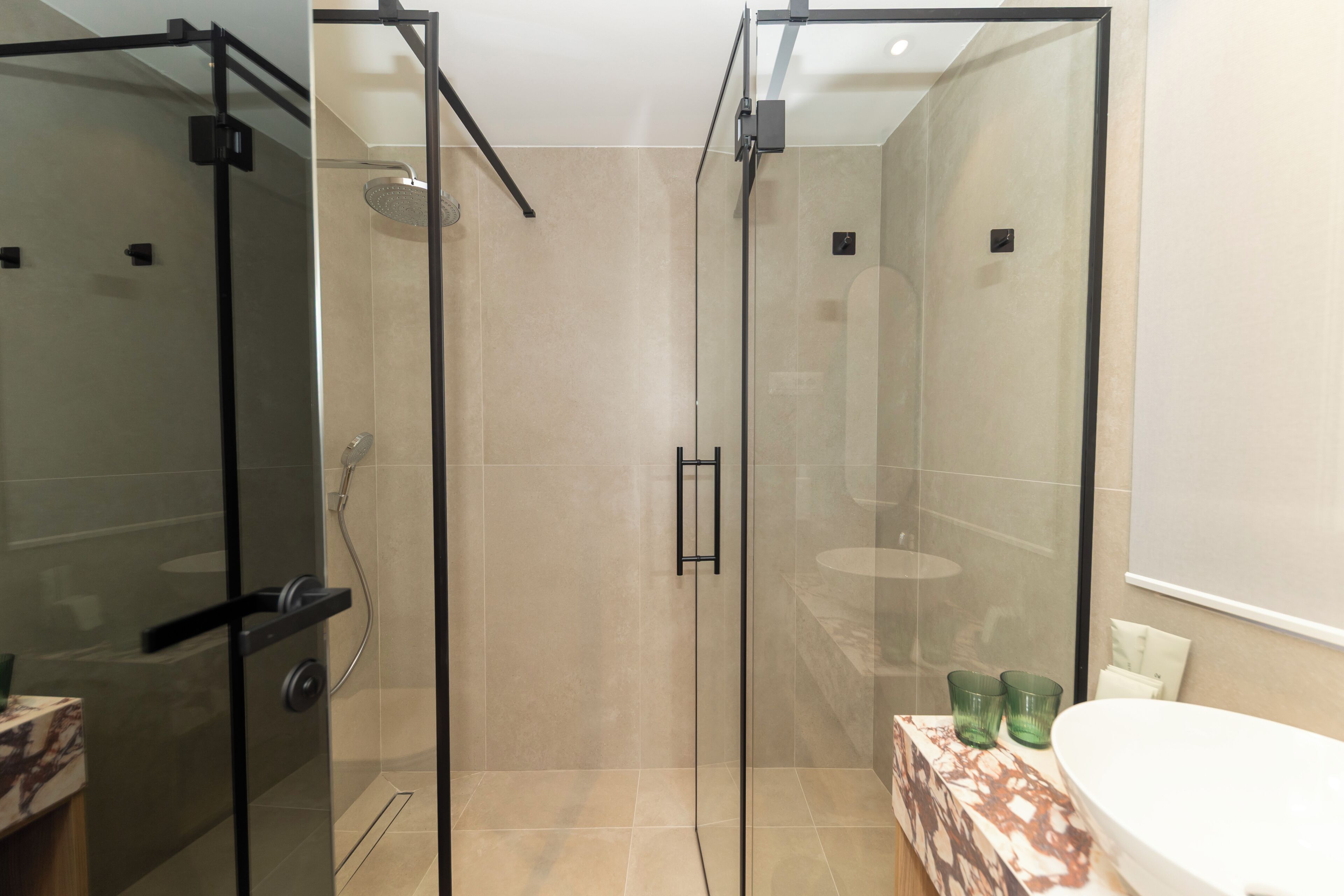 A modern bathroom with a glass-enclosed shower, a marble countertop, and a white sink.
