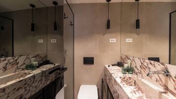 A modern bathroom with a marble vanity, a toilet, and a large mirror.