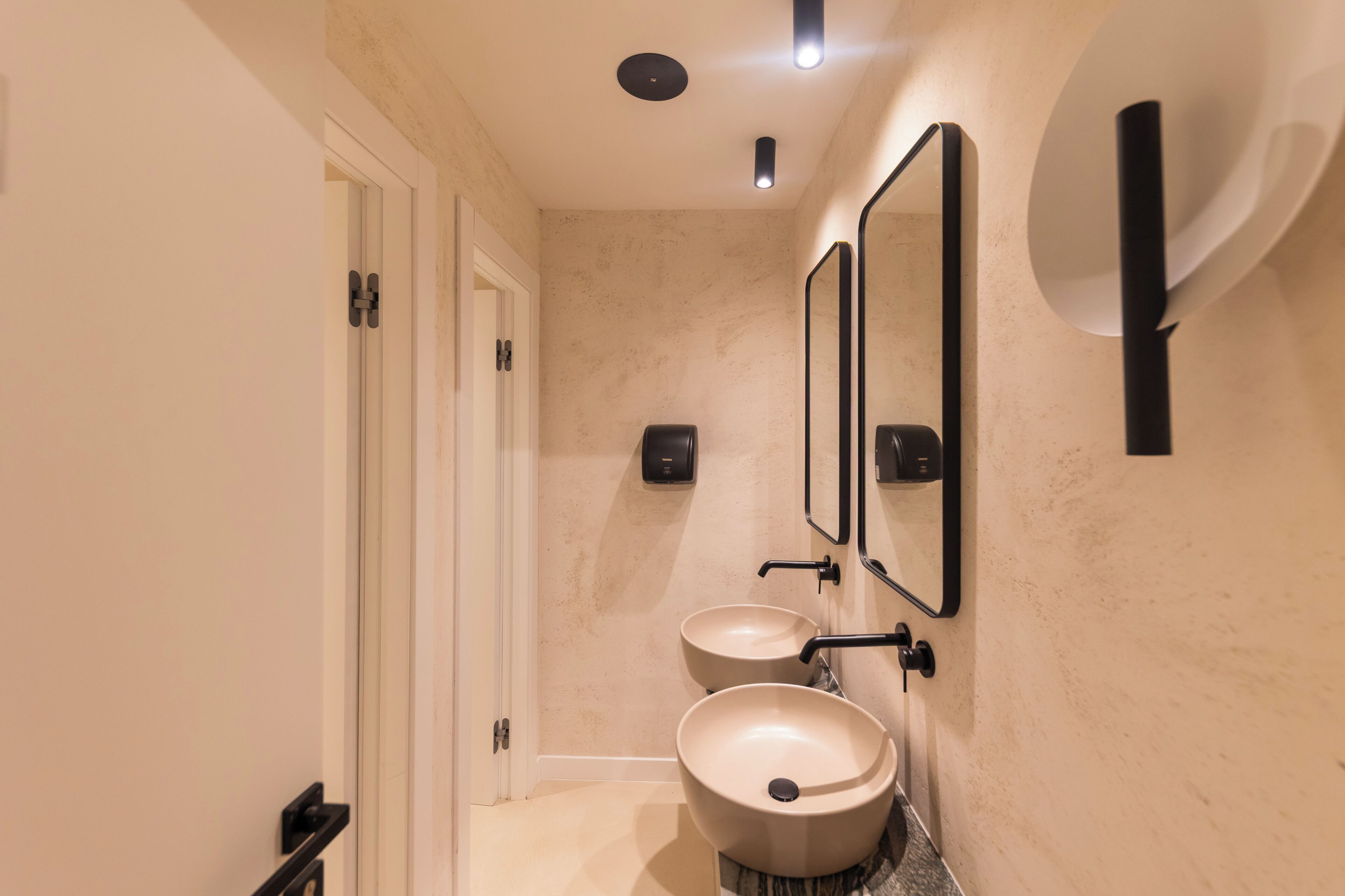 A bathroom with two sinks, a mirror, and a door.