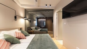 Une chambre à coucher moderne, équipée d’un lit, de lampes de chevet, d’un téléviseur à écran plat et d’un grand miroir.