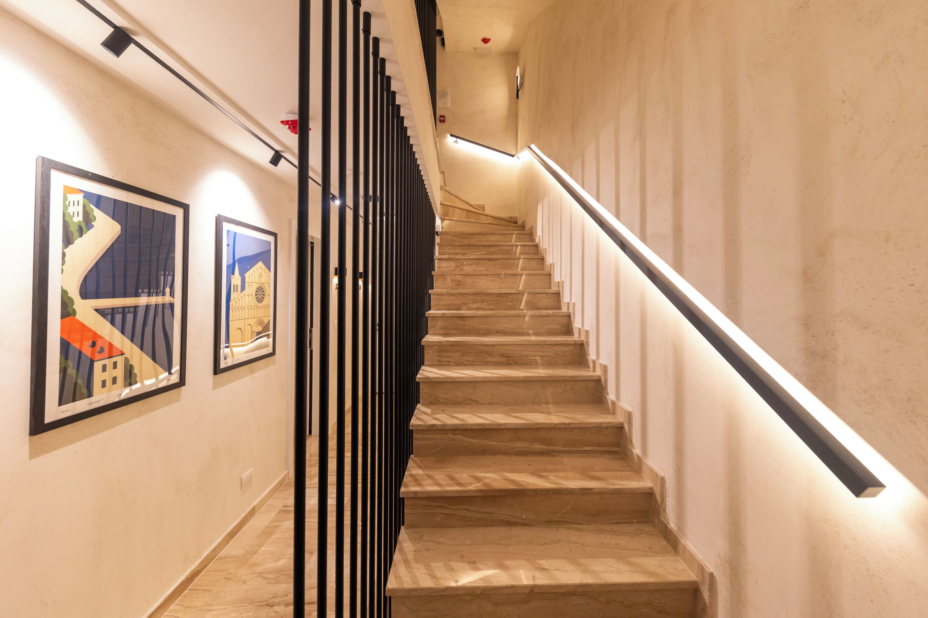 Un escalier au design moderne, doté d’une rampe et d’une bande lumineuse le long du mur.