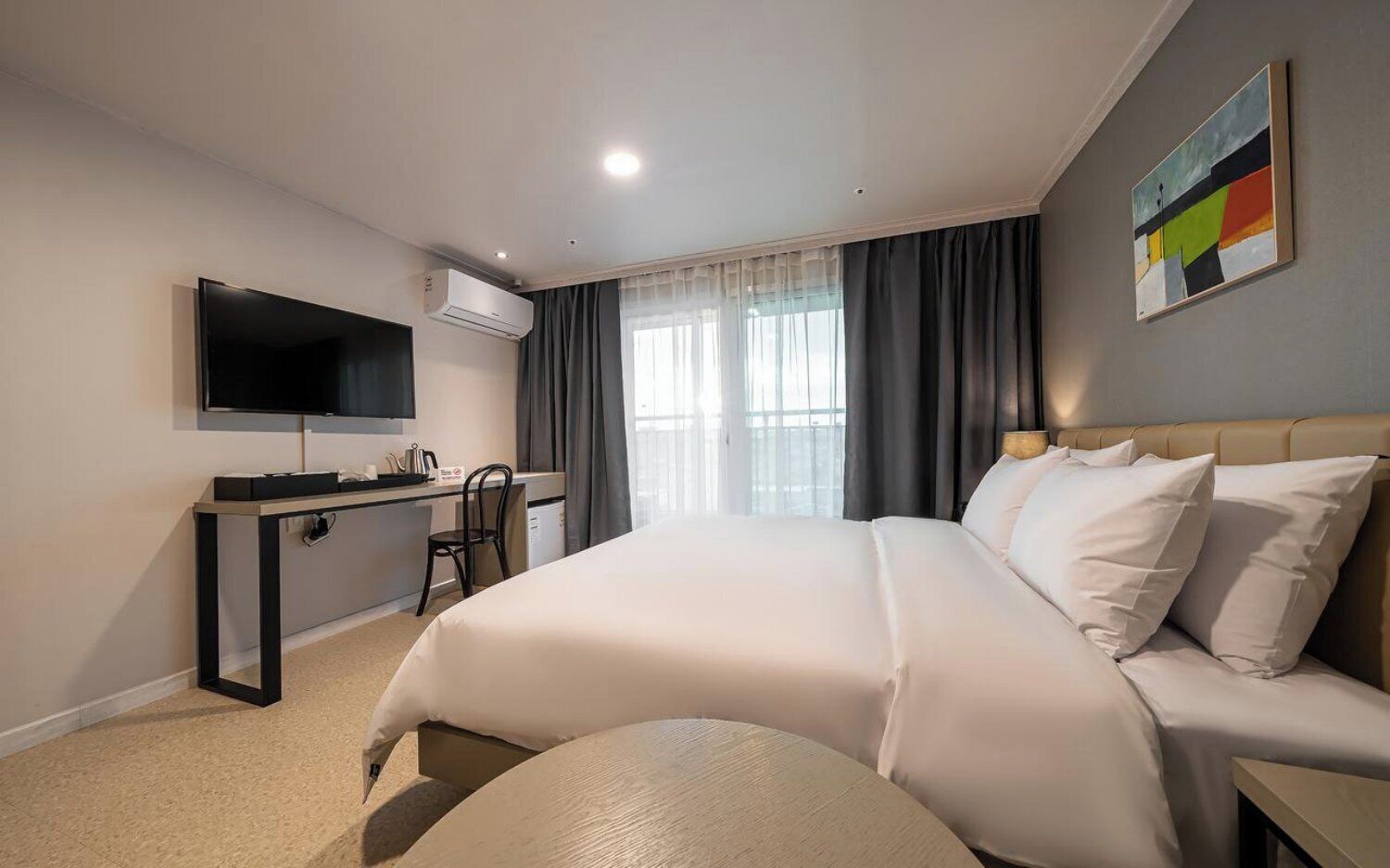 Une chambre d’hôtel avec un lit, un bureau, une télévision et une fenêtre avec des rideaux.