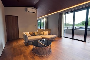 A modern living room with a sectional sofa, a round coffee table, and large sliding glass doors leading to a balcony.