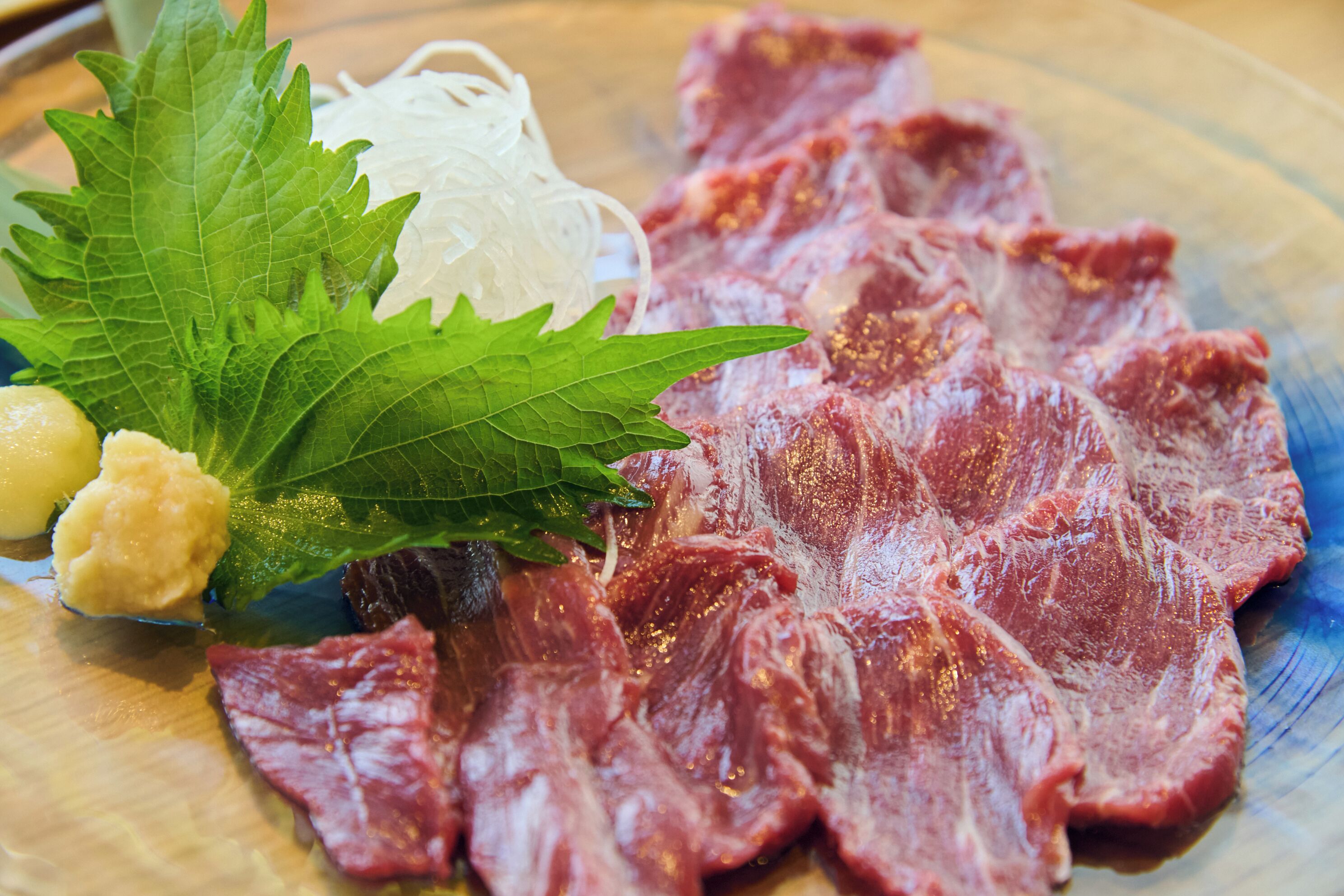 A plate with sliced meat, noodles, and a leaf garnish.