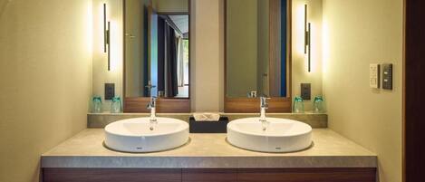 A bathroom with two sinks, a mirror, and a towel rack with towels.