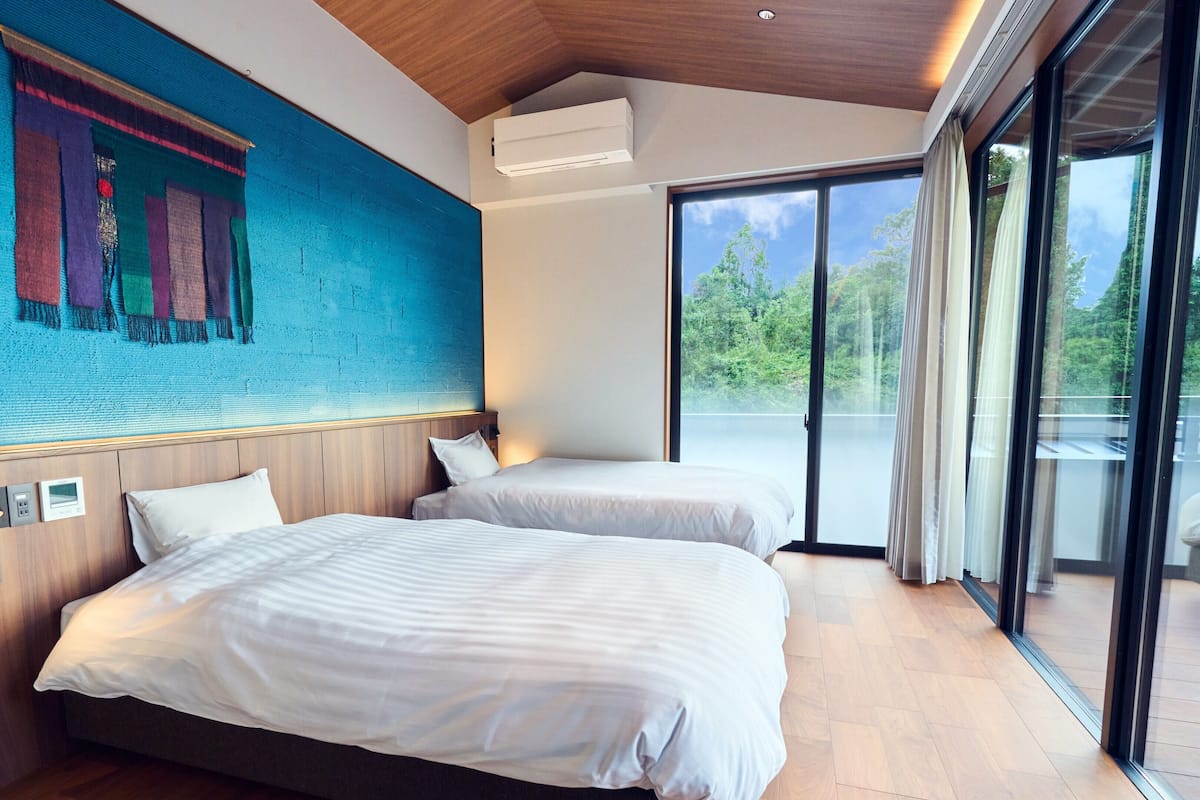 Una habitación de hotel moderna con dos camas, un ventanal grande y vistas al exterior.