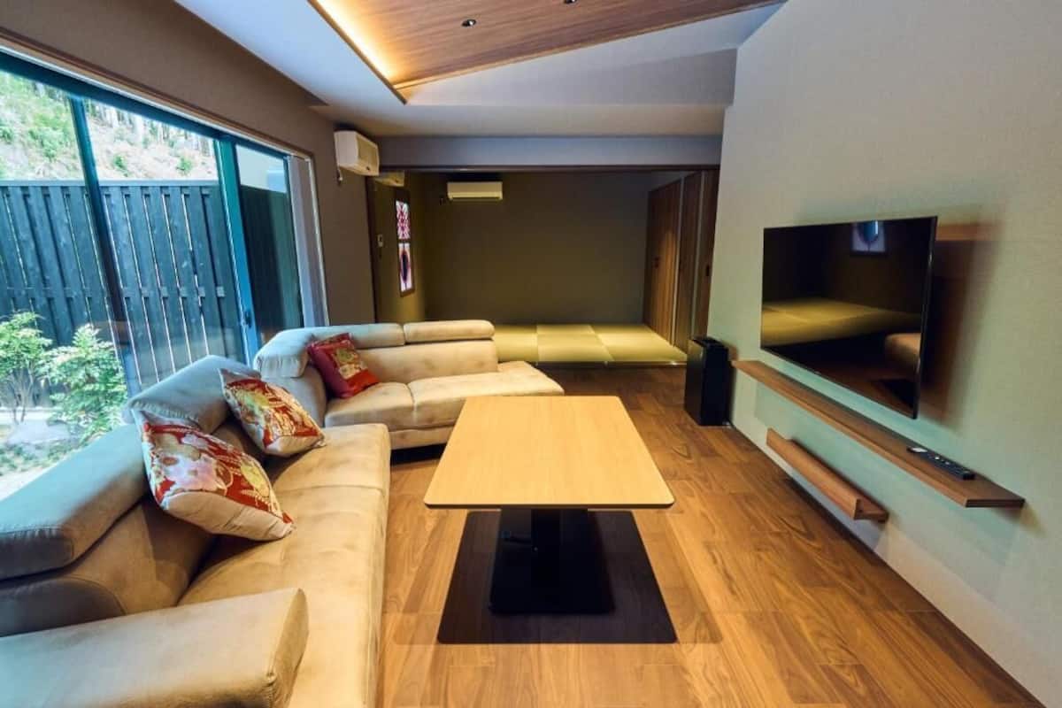 Una sala de estar moderna con un sofá, una mesa de centro, un televisor y piso de madera.