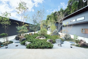 A courtyard with a stone pathway, rock garden, and trees.