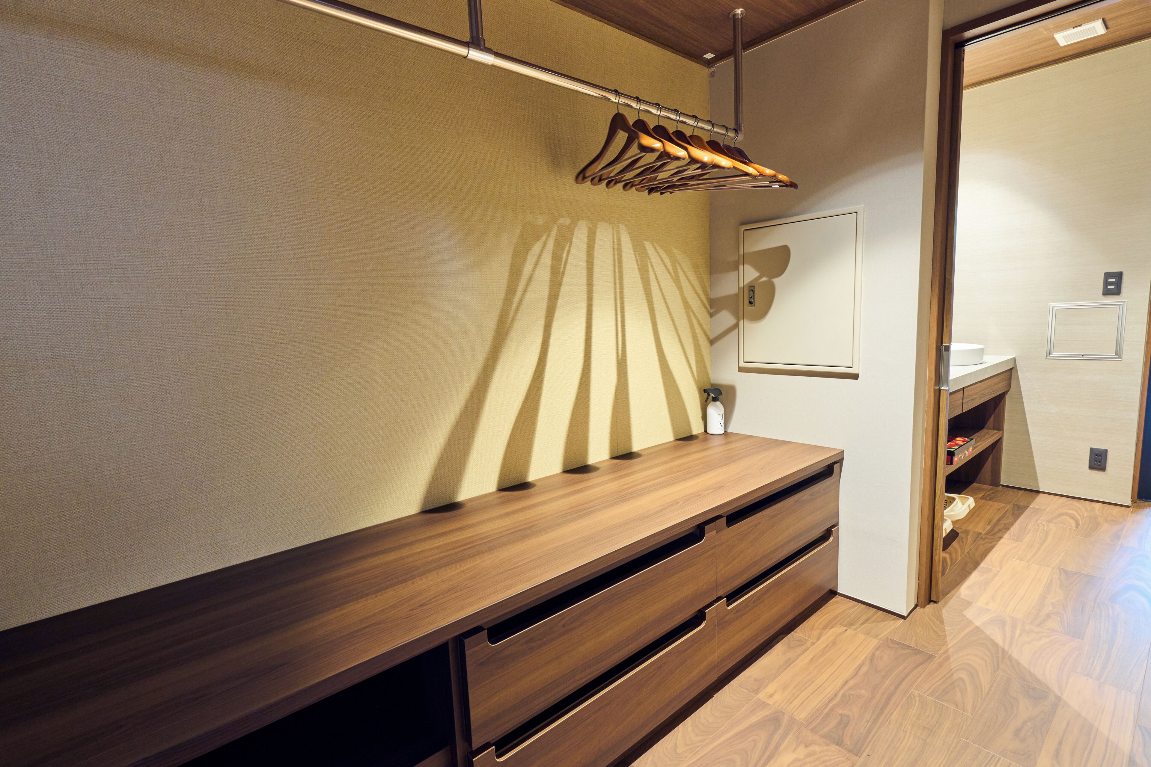 A wooden console table with drawers, a hanging clothes rack, and a wall-mounted light fixture.