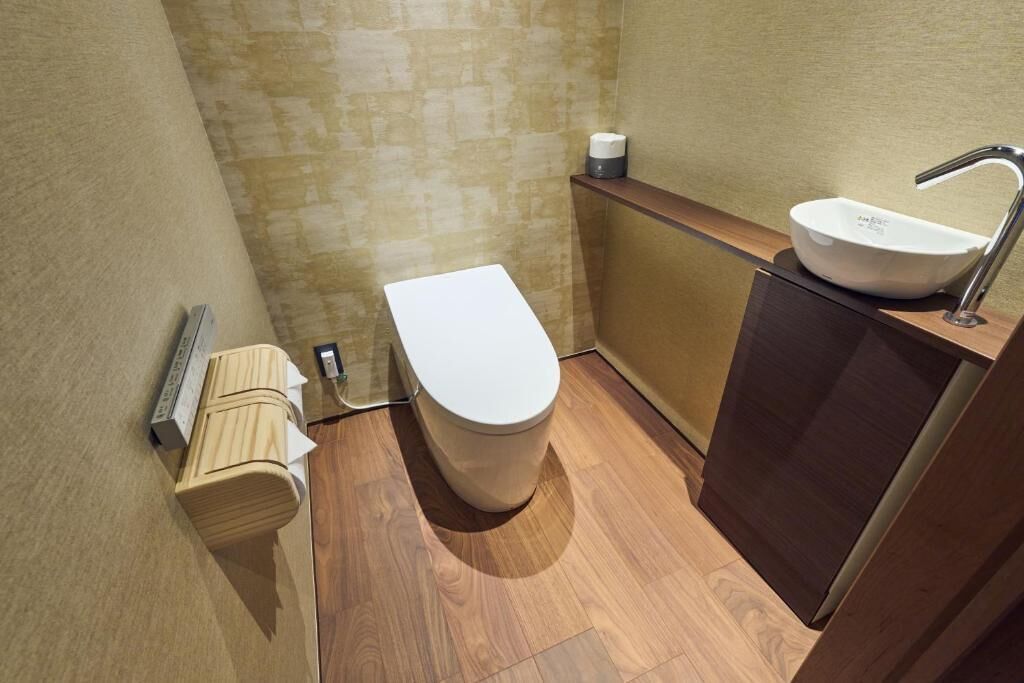 A small, modern bathroom with a toilet, sink, and wooden cabinet.